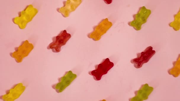 Coloridos osos osos de goma sobre fondo rosa. Detener caramelos de gelatina en movimiento. Industria de dulces
  - Metraje, vídeo