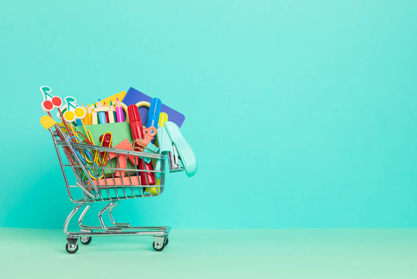 Shopping trolley full of school supplies. Preparation to school, shopping, sale, deals, discounts, promotion concept - Foto, imagen