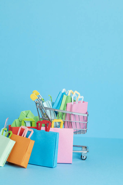 Shopping basket full of paper bags. Sesonal sale, online deals, discounts, promotion, shopping addiction concept - Fotografie, Obrázek
