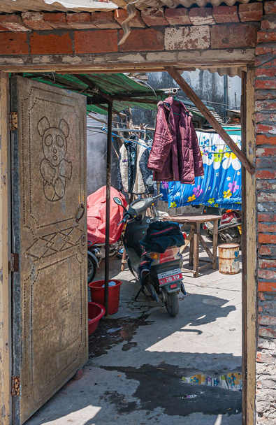 Tongli, JIangsu, China - 3 mei 2010: Hutong netwerk van smalle loopbruggen, eenvoudige huisvesting en kleine bedrijven. Open zware deur met panda afbeelding naar binnenplaats van huis in steegje. wasserij voegt kleur toe. - Foto, afbeelding