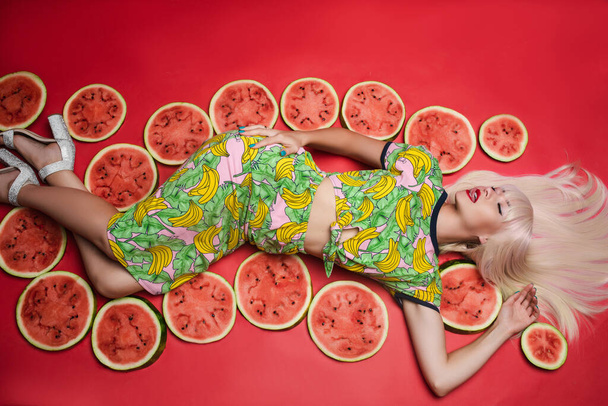 Sexy hermosa joven tumbada en el suelo posando para sesión de fotos rodeada de sandía
 - Foto, imagen