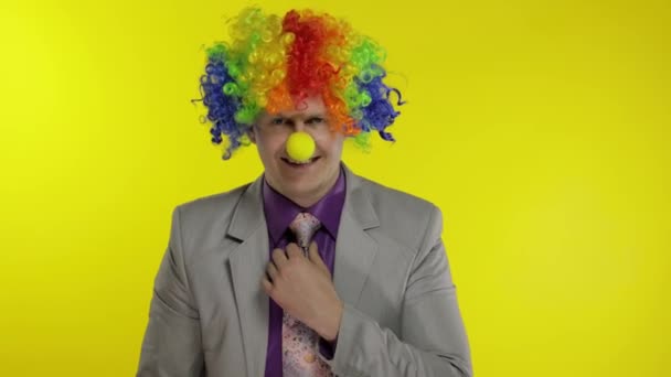 Clown businessman entrepreneur boss in wig adjusts his tie. Yellow background - Footage, Video