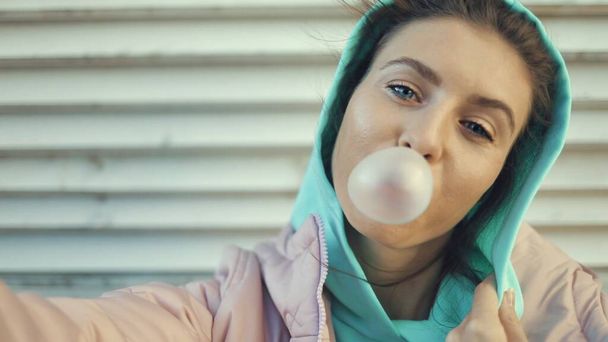 Young woman blowing a bubble gum balloon - Фото, изображение
