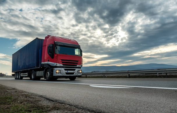  Rood vervoer oplegger vrachtwagen op een snelweg rijden bij heldere zonnige zonsondergang. Vervoer voertuig - Foto, afbeelding