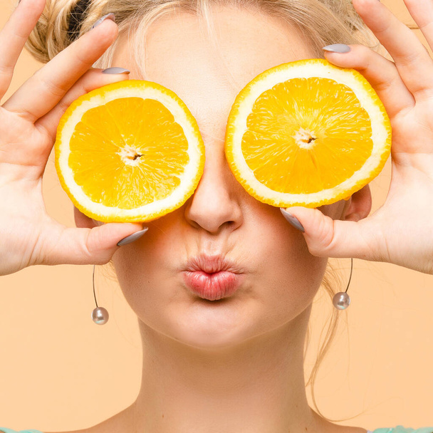 Wesoła młoda blondynka pozująca ze świeżymi pomarańczami - Zdjęcie, obraz