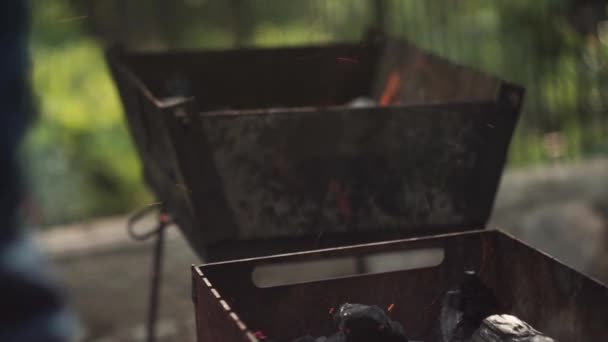 Primer plano. Ventilación manual de un fuego con una pala en una parrilla de barbacoa
 - Metraje, vídeo