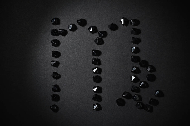 Symbol znaku zodiaku Panna wykonana przez czarne kamienie na czarnym tle. Niski poziom mroku. Oświetlenie winietowe. Temat horoskopu - Zdjęcie, obraz