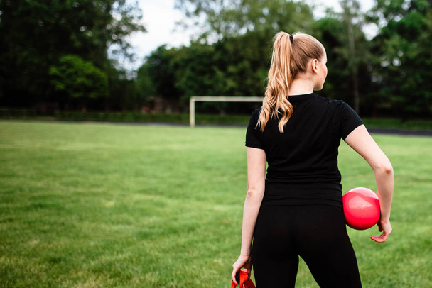 Healthy sports lifestyle. Athletic young woman in a sports dress doing fitness exercises. Fitness woman at the stadium. Young girl holding a tool for sports. Sport. Bag. The girl is holding a bag. - Photo, image