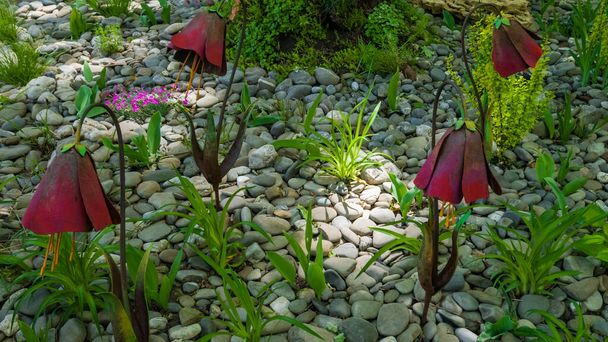 Metalowe kwiaty z czerwonym wieczkiem na kwietniku z zieloną trawą i szarymi kamieniami w parku. Kontekst - Zdjęcie, obraz