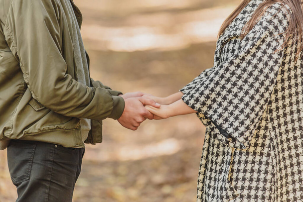 Cropped photo of couple in love holding hands in autumn nature with sunrays everywhere. - Fotó, kép