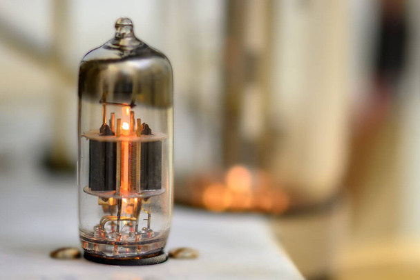 A single glowing vacuum tube. Other tube blowing in the background but outside the shallow depth of field. - Photo, Image