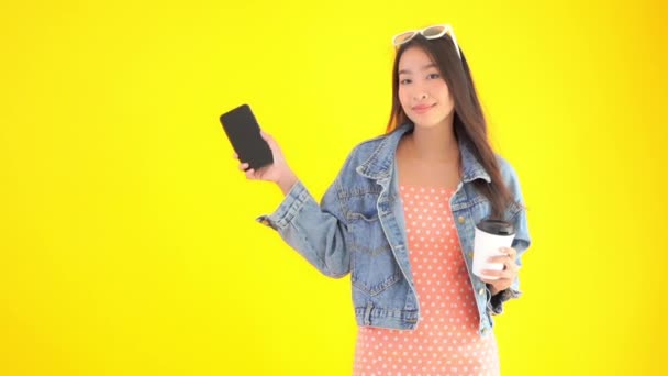 footage of beautiful asian woman with paper cup of coffee and smartphone - Materiał filmowy, wideo