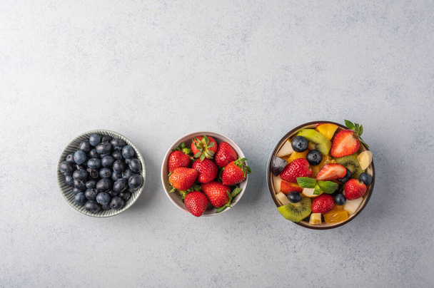 Fresh fruit salad with different ingredients on light wooden background. Healthy diet. Copy space for text. Top view - 写真・画像