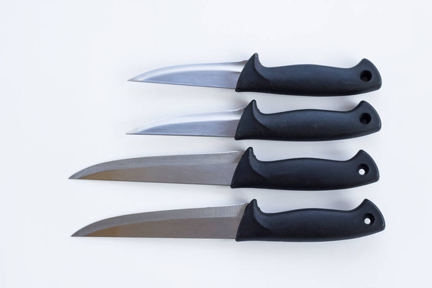 Un grupo de cuchillos de diferentes tamaños en tierra blanca
. - Foto, imagen