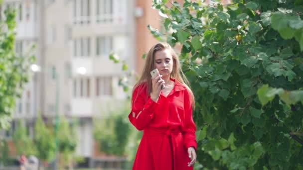 Sad woman in red dress in the city. Beautiful lady holding the mobile phone and becomes happy after calling somebody outdoors. Slow motion. - Metraje, vídeo