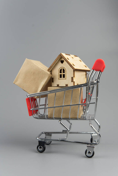 Buying a house, building repair and mortgage concept. Estimation real estate property with loan money and banking. House in shopping cart on grey background. - Foto, Imagem