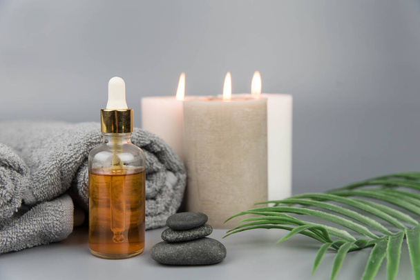Towel with aromatic candles and bottle with natural organic oil essence serum. Aromatherapy and beauty. Concept set of harmony, balance and meditation, spa, massage, relax, beauty spa treatment. - Foto, Bild