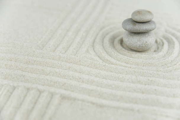 Zen bahçesi. Beyaz ve gri Zen taşlarından piramitler soyut dalga çizimleriyle beyaz kumun üzerinde. Uyum kavramı, denge ve meditasyon, spa, masaj, rahatlama. - Fotoğraf, Görsel