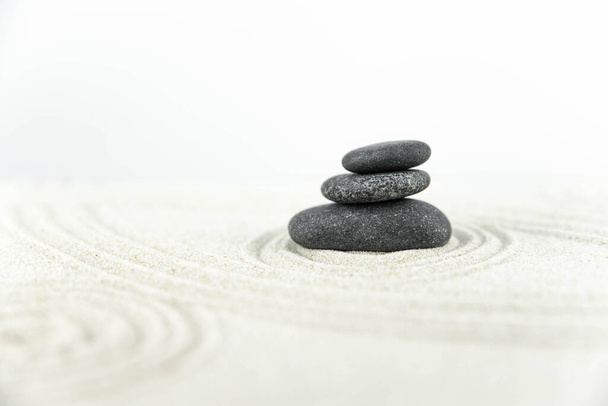 Zen bahçesi. Beyaz ve gri Zen taşlarından piramitler soyut dalga çizimleriyle beyaz kumun üzerinde. Uyum kavramı, denge ve meditasyon, spa, masaj, rahatlama. - Fotoğraf, Görsel