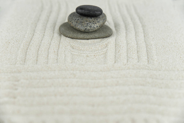 Κήπος Ζεν. Πυραμίδες από άσπρες και γκρι ζεν πέτρες στη λευκή άμμο με αφηρημένα κυματικά σχέδια. Έννοια της αρμονίας, της ισορροπίας και του διαλογισμού, spa, μασάζ, χαλάρωση. - Φωτογραφία, εικόνα