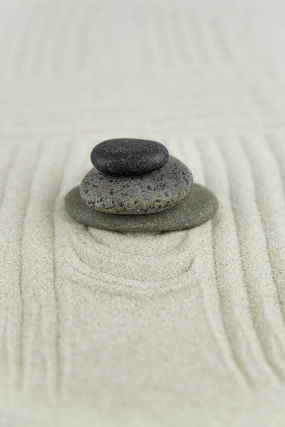 禅の庭。白い砂の上に白と灰色の禅の石のピラミッドの抽象的な波の図面。調和、バランスと瞑想、スパ、マッサージ、リラックスの概念. - 写真・画像