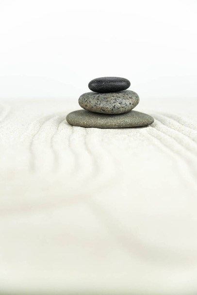 Zen kert. Fehér és szürke zen kövek piramisai a fehér homokon absztrakt hullámrajzokkal. Fogalom harmónia, egyensúly és meditáció, spa, masszázs, pihenés. - Fotó, kép