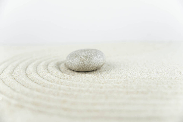 Сад дзен. Піраміди з білого і сірого каменів дзен на білому піску з абстрактними хвильовими малюнками. Концепція гармонії, рівноваги та медитації, спа, масаж, розслабтеся
. - Фото, зображення