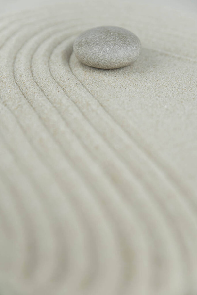 禅の庭。白い砂の上に白と灰色の禅の石のピラミッドの抽象的な波の図面。調和、バランスと瞑想、スパ、マッサージ、リラックスの概念. - 写真・画像