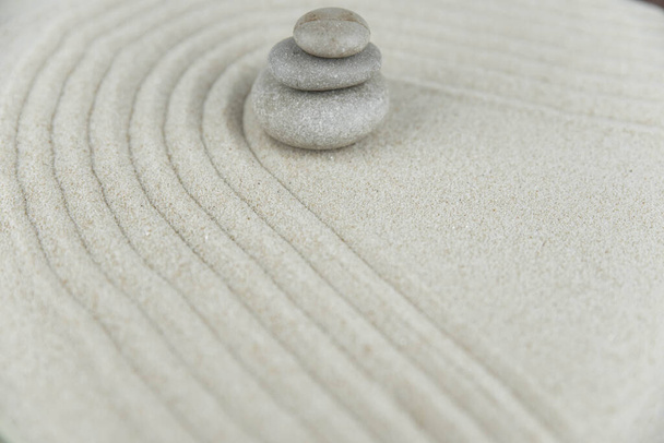 Дзен-сад. Пирамиды белого и серого дзен-камней на белом песке с абстрактными волновыми рисунками. Концепция гармонии, баланса и медитации, спа, массажа, отдыха. - Фото, изображение
