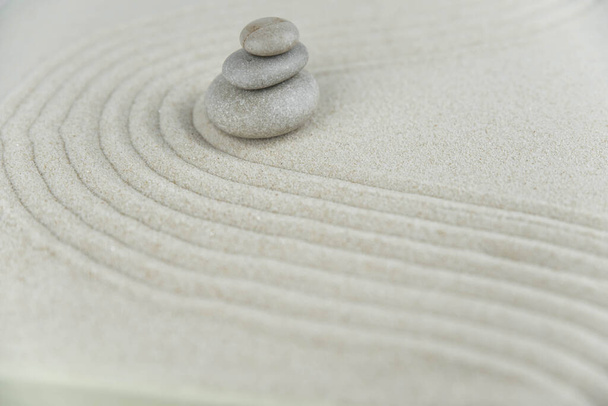 Zen kert. Fehér és szürke zen kövek piramisai a fehér homokon absztrakt hullámrajzokkal. Fogalom harmónia, egyensúly és meditáció, spa, masszázs, pihenés. - Fotó, kép