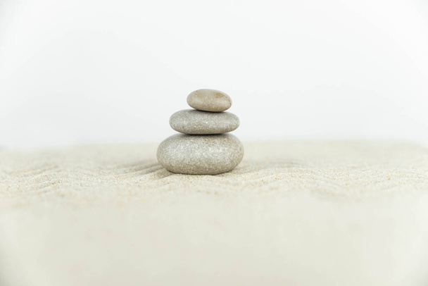 Zen garden. Pyramids of white and gray zen stones on the white sand with abstract wave drawings. Concept of harmony, balance and meditation, spa, massage, relax. - Foto, Bild