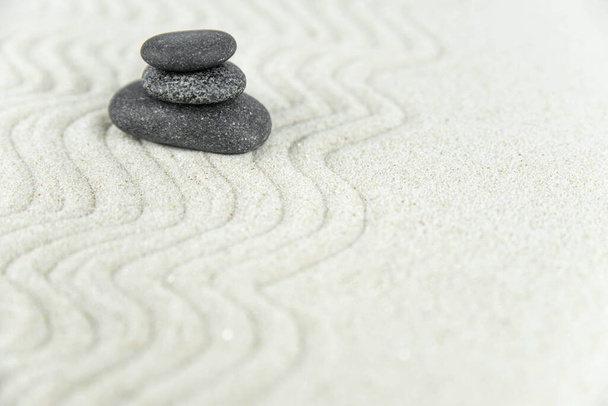 Zen garden. Pyramids of white and gray zen stones on the white sand with abstract wave drawings. Concept of harmony, balance and meditation, spa, massage, relax. - Photo, image
