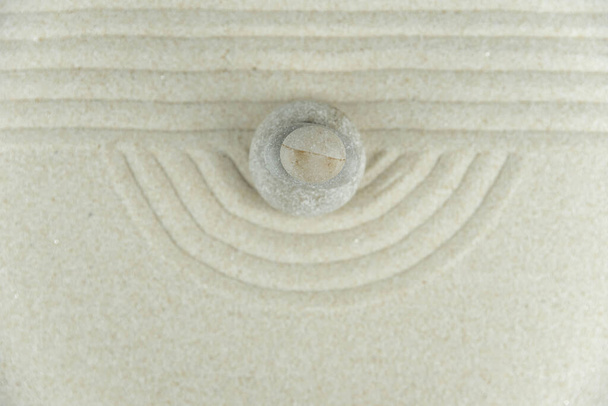 Zen tuin. Piramides van witte en grijze zen stenen op het witte zand met abstracte golftekeningen. Concept van harmonie, balans en meditatie, spa, massage, ontspannen. - Foto, afbeelding