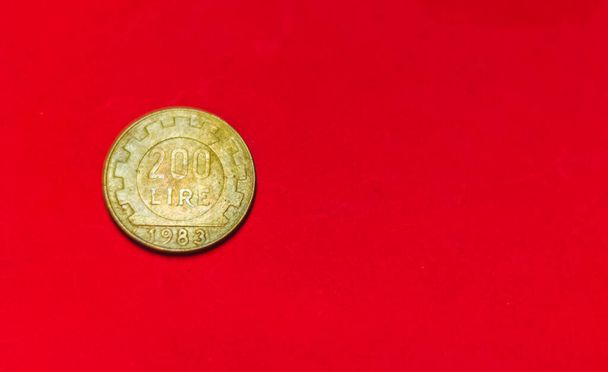 Olasz 200 líra érmé.Régi használt kétszáz olasz líra, 1983. Vintage bronz érme elszigetelt piros háttérrel helyet a szöveges másolatot. repvbblica italiana 200 - Fotó, kép