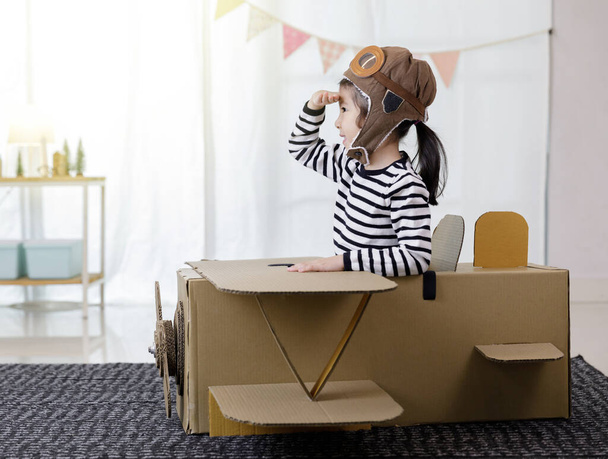 Aasian pieni lapsi tyttö leikkii pahvi lelu lentokone käsityö eristetty kotona kopio tilaa tekstin, Creative perheen ja haaveilee lentävät käsite - Valokuva, kuva