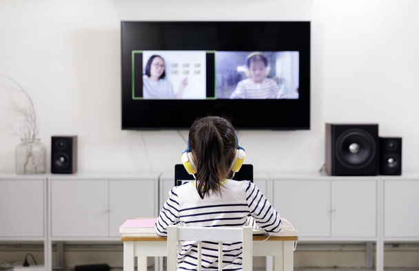Écolière asiatique apprenant à la maison avec ordinateur portable à l'aide d'un appel vidéo avec son professeur, distance sociale pendant l'isolement en quarantaine pendant le Coronavirus (COVID-19) soins de santé
 - Photo, image