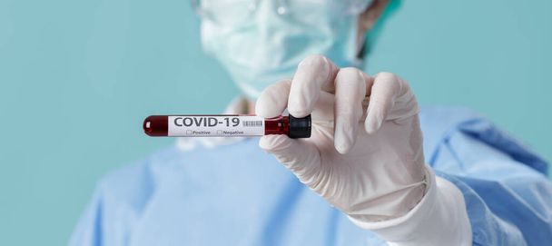 Coronavirus Salgını 'nı (COVID-19) durdurmak için solunum maskesi takan hemşire ve Corona Virüsü için test edilen hastaların kan örneklerini laboratuvarda, boş alanda uzun pankartta tutuyor. - Fotoğraf, Görsel