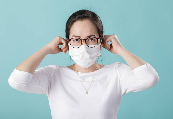 Mujer joven asiática que usa máscara respiratoria para proteger el brote de coronavirus y lavarse las manos con gel de alcohol, nuevo virus Covid-19 de Wuhan China concepto, aislado sobre fondo azul
 - Foto, imagen