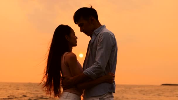 Романтична молода пара обіймається на пляжі на заході сонця
 - Кадри, відео
