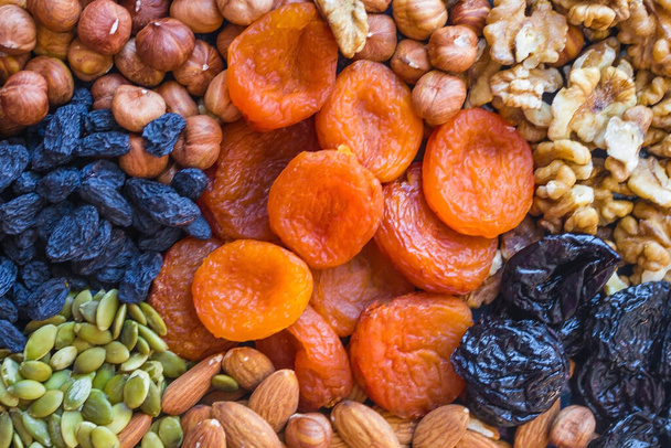 Set noten van verschillende soorten, gedroogde abrikozen, rozijnen en pompoenpitten. Bruin, groen, oranje en zwart. Juiste, evenwichtige voeding, mager voedsel, dieet. - Foto, afbeelding