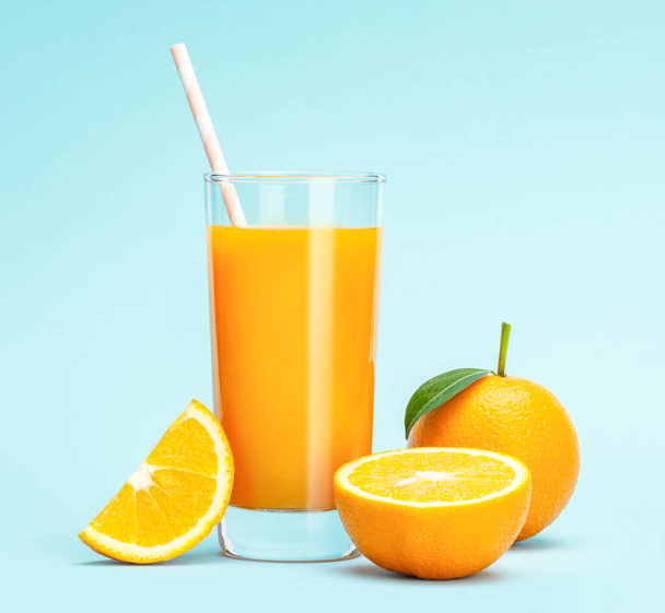 Glass of fresh orange juice on wooden table, Fresh fruits Orange juice in glass with group of orange on blue background, Selective focus on glass - Foto, afbeelding