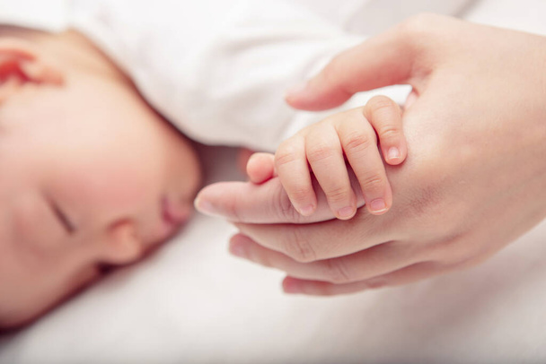 Mão o bebê adormecido na mão da mãe close-up (foco suave e embaçado
) - Foto, Imagem