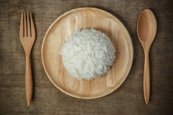 Vista superior del arroz jazmín tailandés en plato de madera con napería y cuchara de madera, alimentos orgánicos y concepto saludable
 - Foto, Imagen