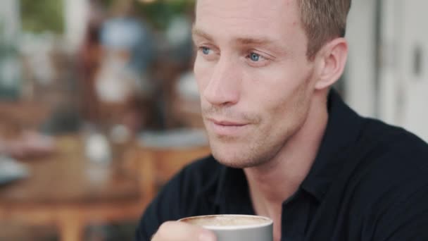 Portrait of blond man drinking coffee in cafe and thinking about something - Materiaali, video