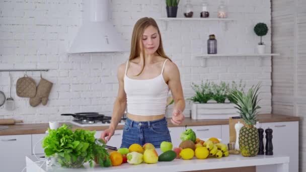 Cheerful female with broccoli at home. Sportive young woman choosing healthy diet full of minerals and vitamins in the kitchen. Girl standing near fresh fruit and vegetables. - Séquence, vidéo