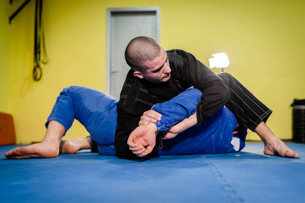 Brazilský Jiu jitsu BJJ jiujitsu trénink sportovní bojovník použití kimura rameno zámek podání na svého soupeře během tréninku techniky - Fotografie, Obrázek
