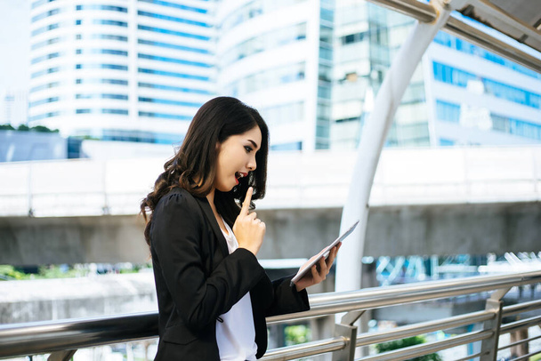 Atrakcyjna kobieta biznesowa korzystająca z tabletu cyfrowego stojąca przed budynkiem biurowym. - Zdjęcie, obraz