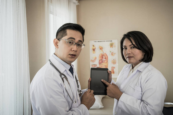 Два врача обсуждают работу. Во время просмотра планшета вместе в больнице
. - Фото, изображение