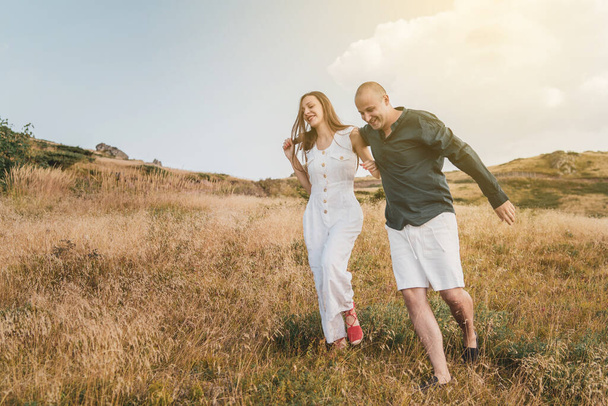 Молода пара чоловік і жінка в любові ходять на полі на горі в осінній або літній день обіймаючись разом, веселячись фліртуючим чоловіком і коханцями дружини
 - Фото, зображення
