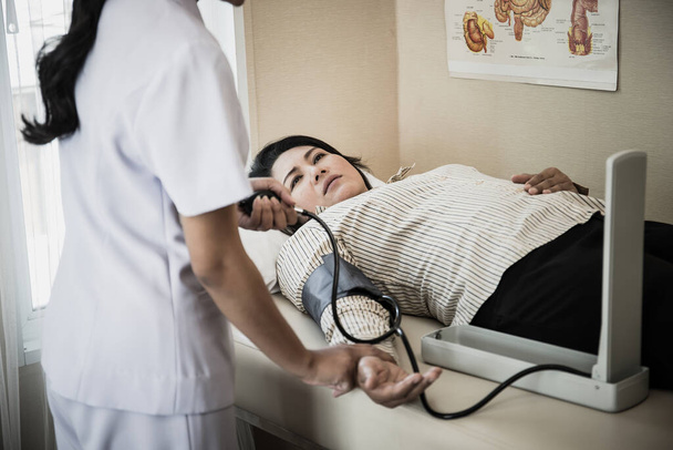 入院中の血圧を測定する高齢患者の看護を若い看護師の終わります - 写真・画像